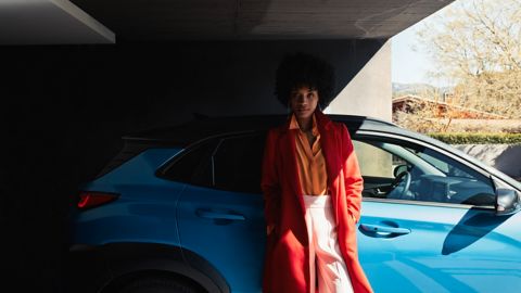 Žena, opírající se o Hyundai KONA Hybrid.